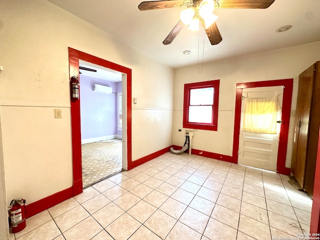 empty room with a wall mounted AC, light tile patterned floors, and ceiling fan