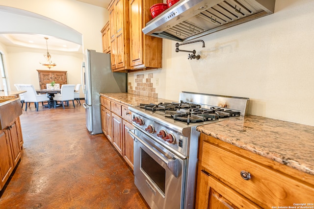 kitchen with pendant lighting, ventilation hood, a tray ceiling, light stone counters, and stainless steel appliances