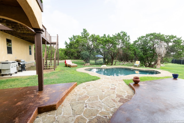 view of swimming pool featuring a grill, a lawn, and a patio area