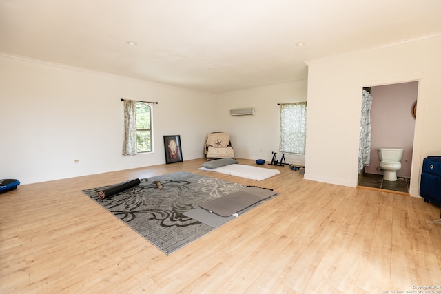 exercise room with ornamental molding, light hardwood / wood-style floors, and an AC wall unit