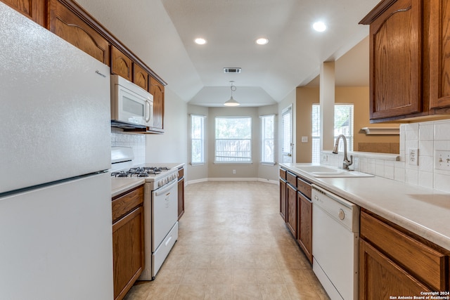 kitchen featuring pendant lighting, sink, tasteful backsplash, white appliances, and vaulted ceiling