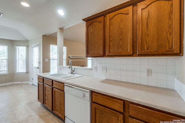 kitchen with vaulted ceiling, decorative backsplash, sink, and dishwasher