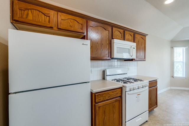 kitchen featuring decorative backsplash, white appliances, and vaulted ceiling