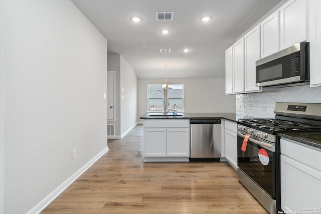 kitchen featuring appliances with stainless steel finishes, decorative light fixtures, white cabinetry, sink, and kitchen peninsula