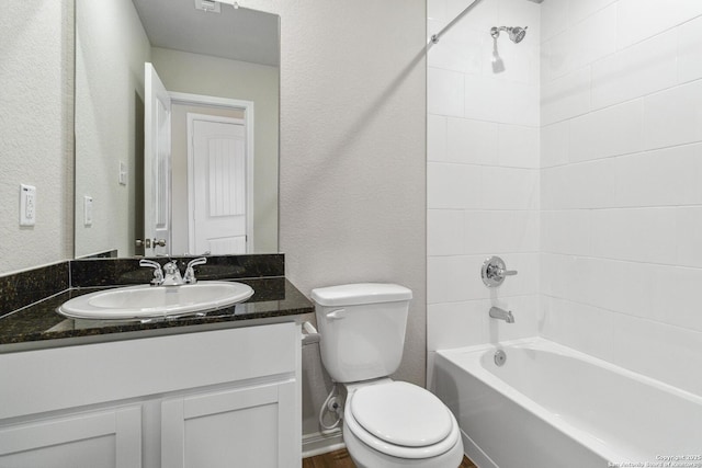 full bathroom featuring vanity, tiled shower / bath, and toilet