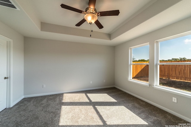 carpeted spare room with ceiling fan and a tray ceiling