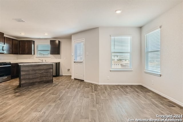 kitchen featuring plenty of natural light, stainless steel stove, light hardwood / wood-style flooring, and dark brown cabinets