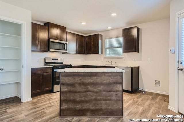 kitchen featuring light hardwood / wood-style floors, dark brown cabinetry, sink, appliances with stainless steel finishes, and a center island