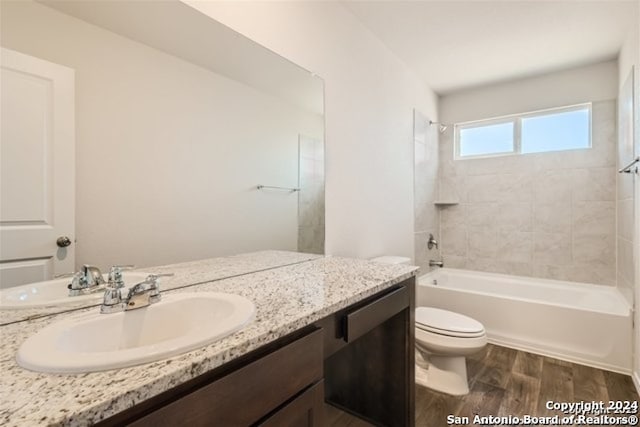 full bathroom featuring tiled shower / bath combo, hardwood / wood-style flooring, vanity, and toilet