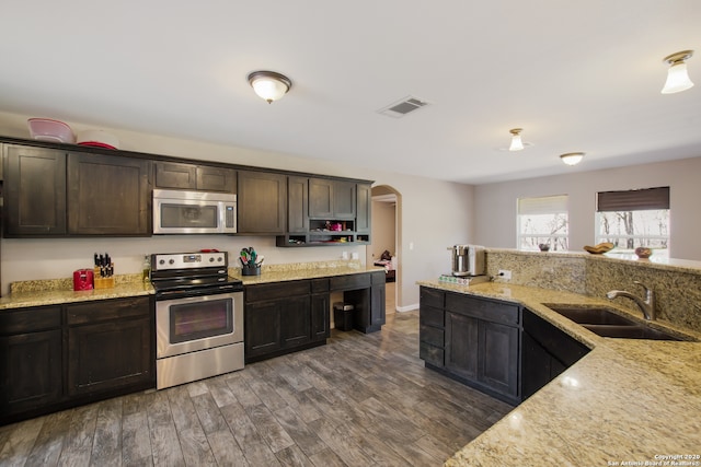 kitchen featuring dark brown cabinets, sink, stainless steel appliances, light stone countertops, and dark hardwood / wood-style floors