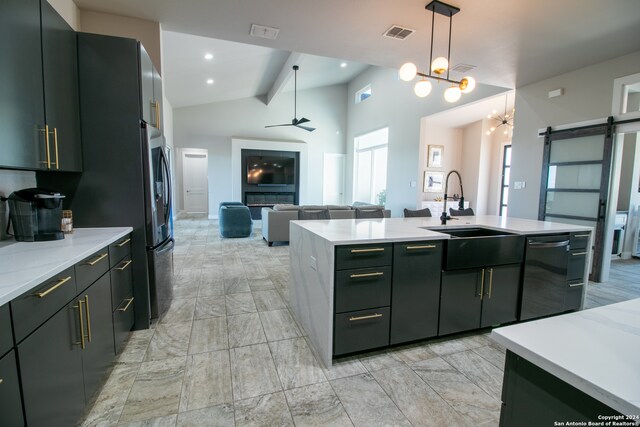 kitchen with stainless steel refrigerator, ceiling fan with notable chandelier, a barn door, black dishwasher, and decorative light fixtures