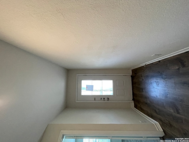 spare room with a textured ceiling and wood walls