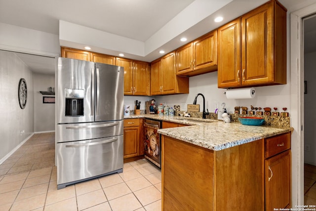 kitchen with light stone counters, stainless steel appliances, sink, kitchen peninsula, and light tile patterned floors