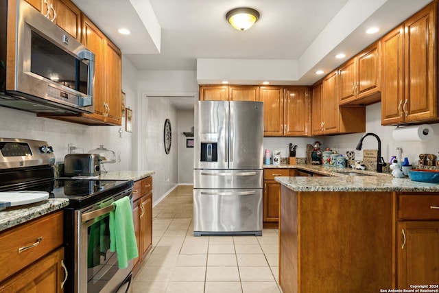 kitchen featuring appliances with stainless steel finishes, sink, light stone counters, and light tile patterned flooring