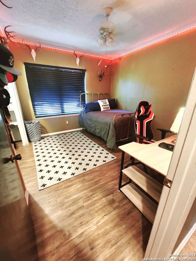 bedroom featuring wood-type flooring, a textured ceiling, and ceiling fan