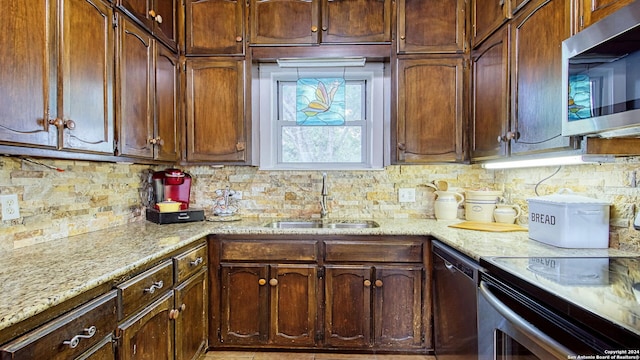 kitchen featuring stainless steel appliances, light stone countertops, sink, and tasteful backsplash