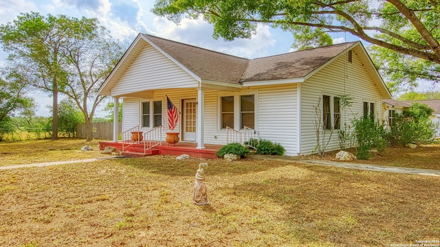 view of front facade with roof with shingles, fence, and covered porch