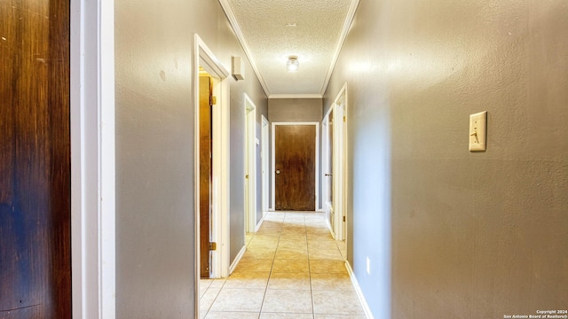 hallway with a textured ceiling, light tile patterned floors, and ornamental molding