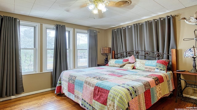 bedroom featuring multiple windows, wood-type flooring, and ceiling fan