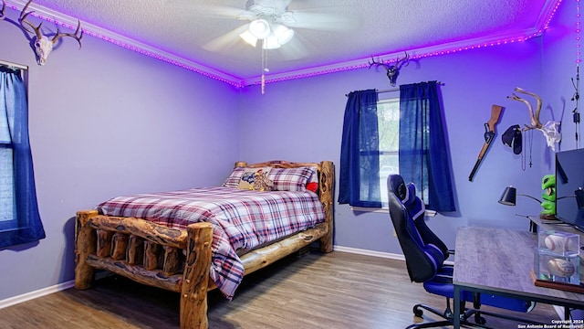 bedroom featuring a textured ceiling, wood-type flooring, ceiling fan, and crown molding