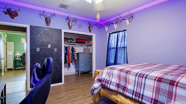 bedroom with a textured ceiling, hardwood / wood-style flooring, ceiling fan, and a closet