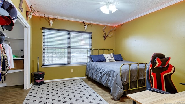 bedroom with hardwood / wood-style flooring, ceiling fan, a textured ceiling, and crown molding