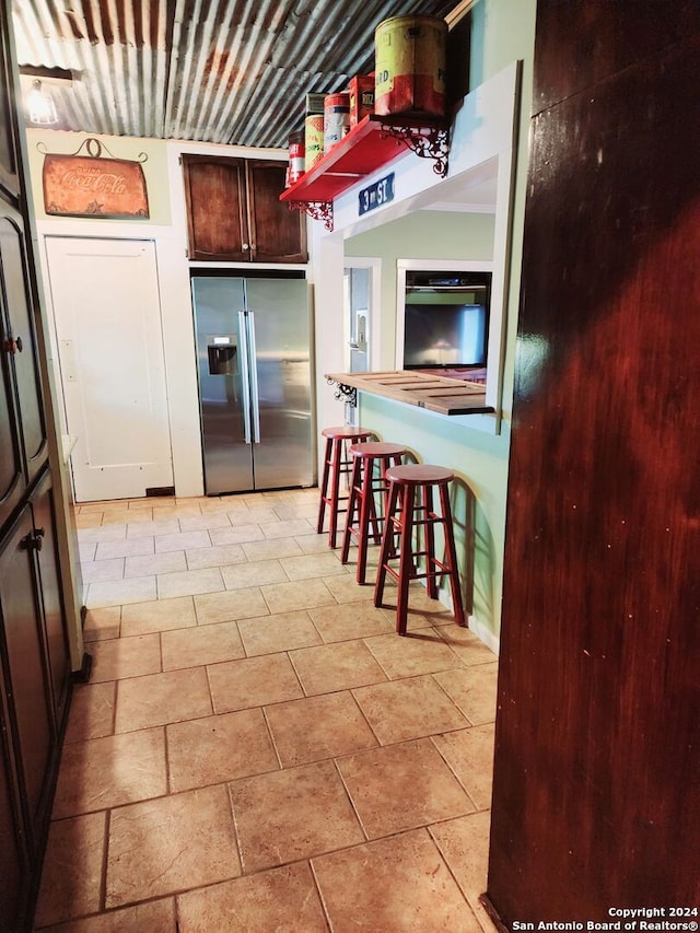 kitchen featuring dark brown cabinets and stainless steel fridge with ice dispenser