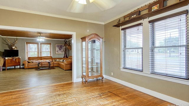 interior space with crown molding, a ceiling fan, baseboards, and wood finished floors