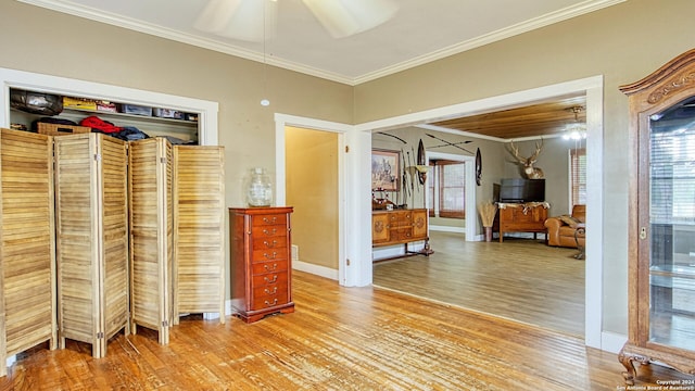 bedroom with crown molding, baseboards, ceiling fan, and light wood-style flooring
