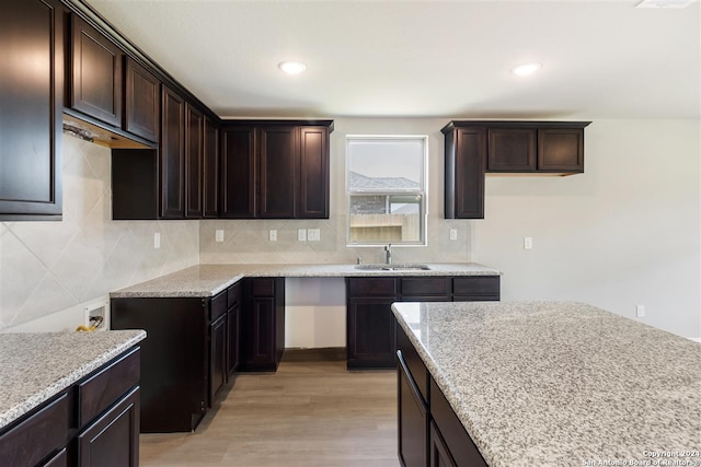 kitchen with light stone countertops, sink, light hardwood / wood-style floors, and decorative backsplash