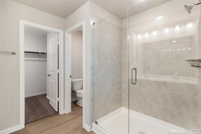 bathroom featuring hardwood / wood-style floors, a shower with door, and toilet