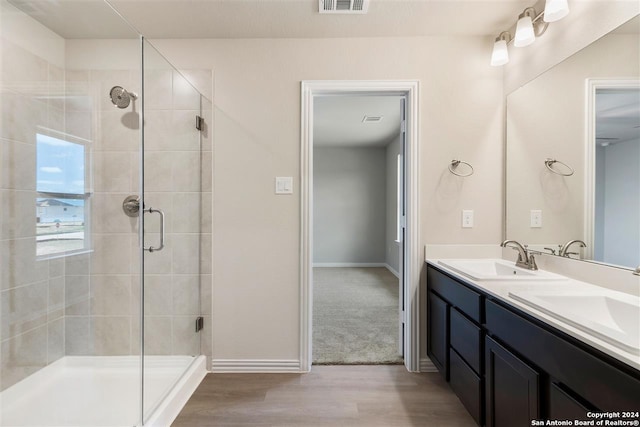 bathroom with wood-type flooring, a shower with door, and vanity