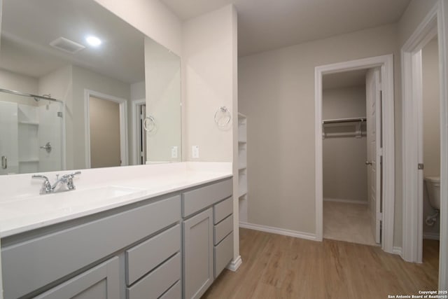 bathroom with vanity, hardwood / wood-style flooring, a shower with shower door, and toilet