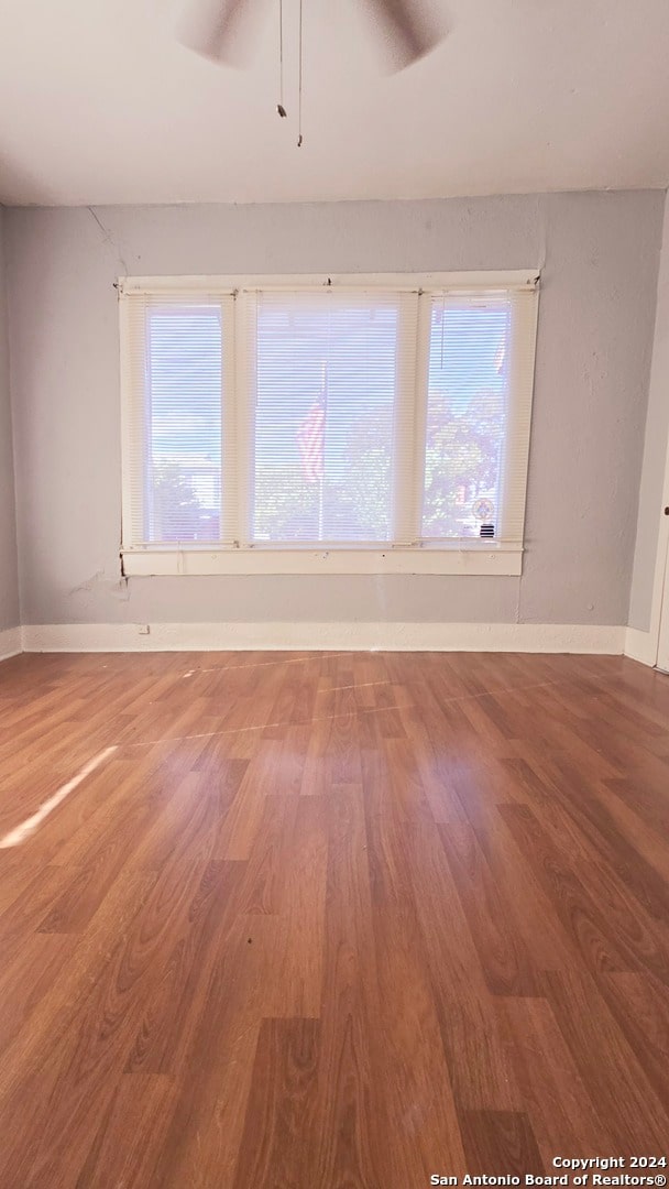 empty room with wood-type flooring, ceiling fan, and a wealth of natural light