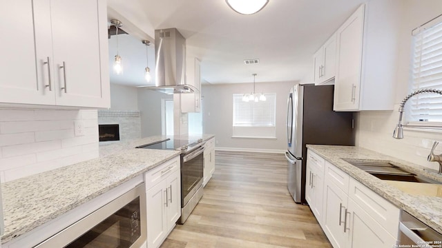 kitchen featuring ventilation hood, sink, hanging light fixtures, white cabinets, and appliances with stainless steel finishes