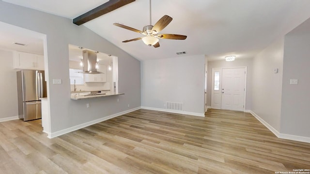 unfurnished living room featuring ceiling fan, light hardwood / wood-style flooring, and lofted ceiling with beams