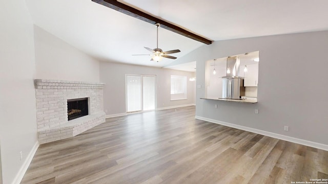 unfurnished living room with ceiling fan, vaulted ceiling with beams, light wood-type flooring, and a brick fireplace