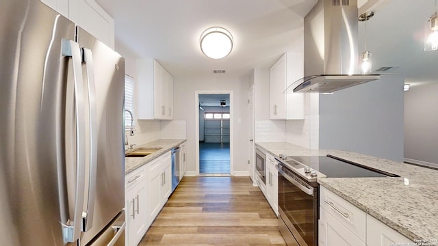 kitchen featuring island exhaust hood, light hardwood / wood-style flooring, white cabinetry, stainless steel appliances, and light stone countertops