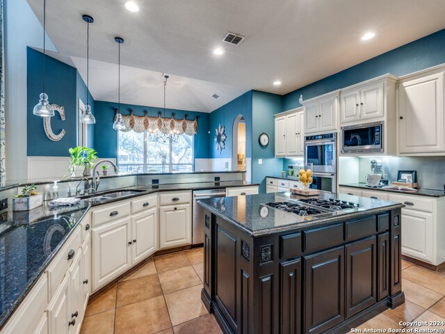 kitchen featuring kitchen peninsula, dark stone countertops, sink, pendant lighting, and appliances with stainless steel finishes