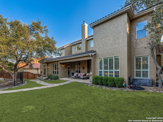 rear view of house with a patio and a lawn