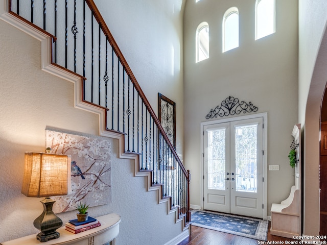 entrance foyer with french doors, wood-type flooring, and a high ceiling