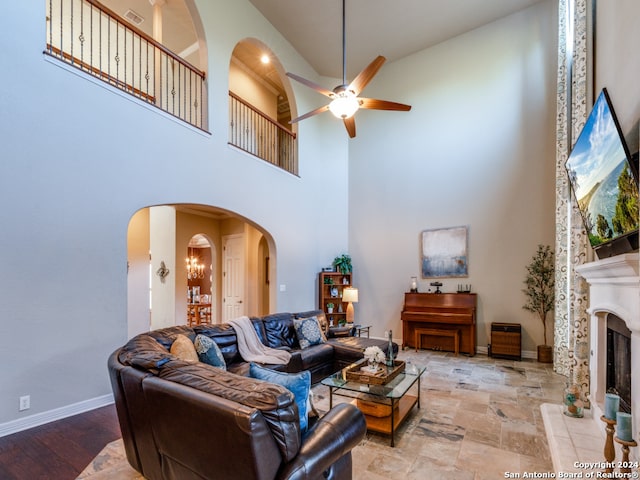 living room with ceiling fan, a towering ceiling, and light hardwood / wood-style flooring