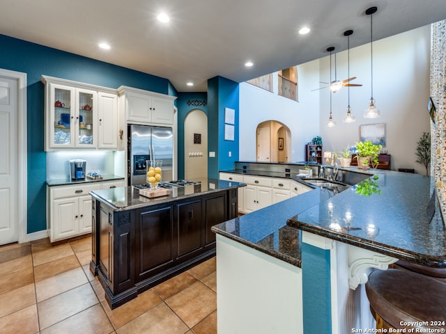 kitchen featuring stainless steel fridge, ceiling fan, a spacious island, pendant lighting, and sink