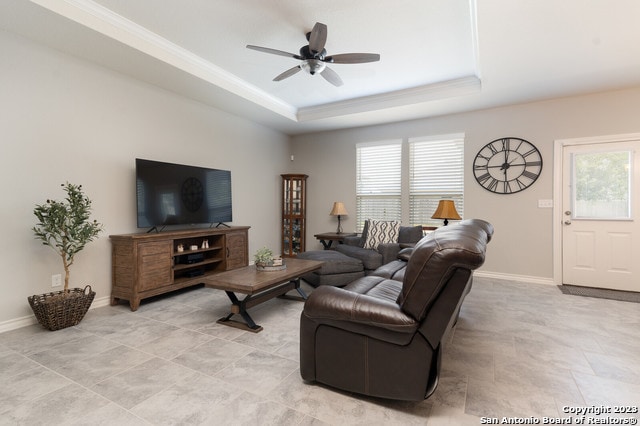 living room featuring a raised ceiling and ceiling fan