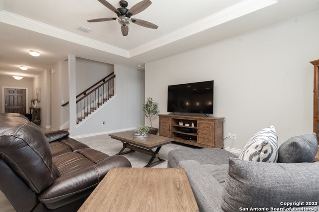 living room featuring crown molding, ceiling fan, and a raised ceiling