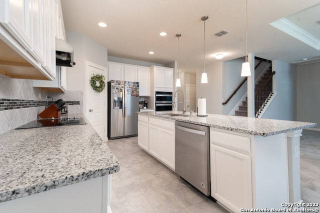 kitchen featuring a center island with sink, pendant lighting, white cabinetry, and stainless steel appliances