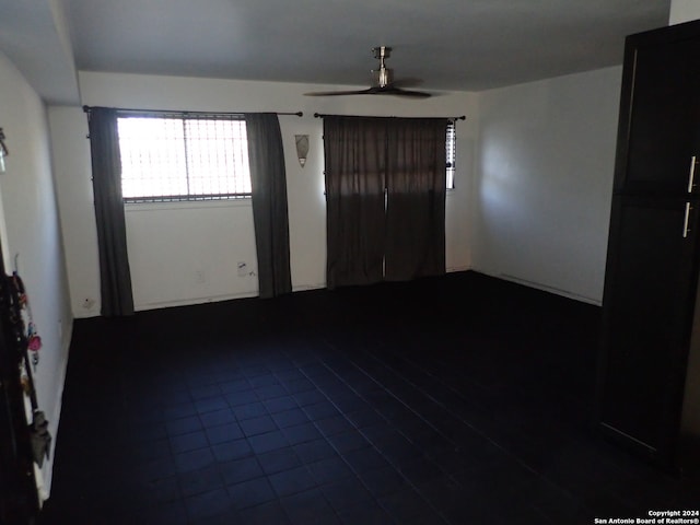 tiled empty room featuring ceiling fan