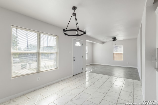 foyer featuring ceiling fan with notable chandelier