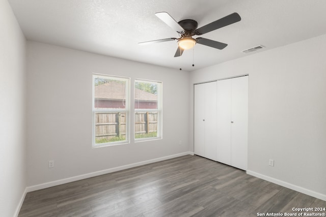 unfurnished bedroom featuring a textured ceiling, ceiling fan, a closet, and dark hardwood / wood-style flooring