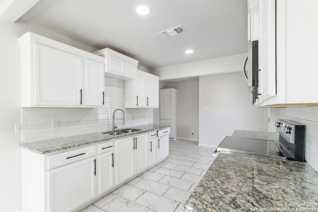 kitchen with stainless steel appliances, sink, light stone counters, and white cabinetry